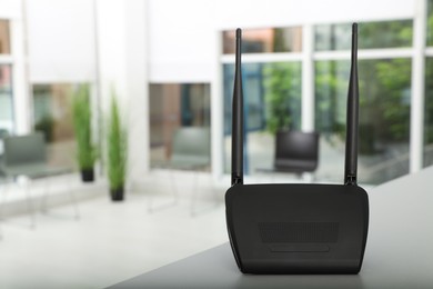 Photo of Modern Wi-Fi router on grey table indoors, space for text