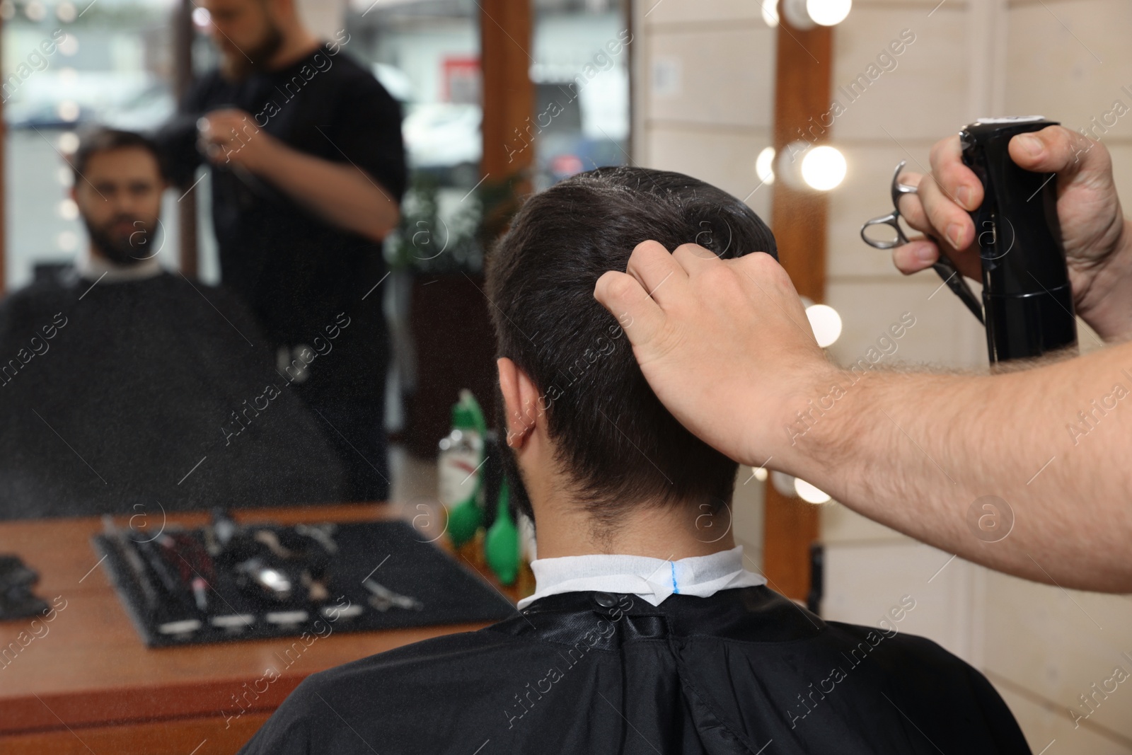 Photo of Professional hairdresser working with client in barbershop, closeup