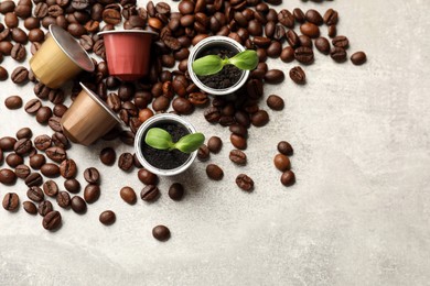 Photo of Coffee capsules with seedlings and beans on light grey table, flat lay. Space for text