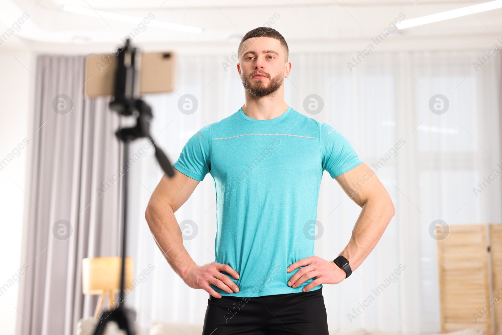 Photo of Trainer streaming online fitness lesson with phone at home