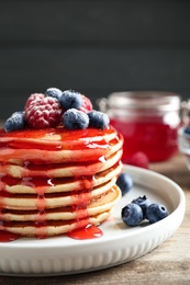 Photo of Delicious pancakes with fresh berries and syrup on wooden table