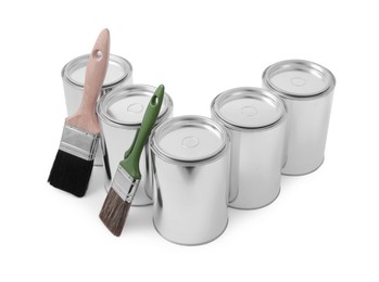 Photo of Cans of paints and brushes on white background