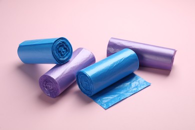 Photo of Rolls of different color garbage bags on pink background