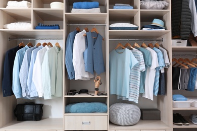 Photo of Stylish clothes, shoes and home stuff in large wardrobe closet