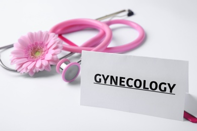 Photo of Card with word Gynecology, clipboard, stethoscope and flower on white background