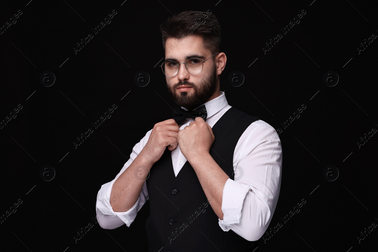 Photo of Portrait of handsome man in shirt and bow tie on black background