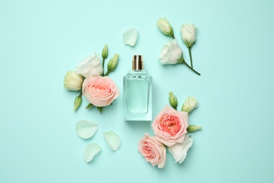 Photo of Flat lay composition with bottle of perfume and flowers on cyan background