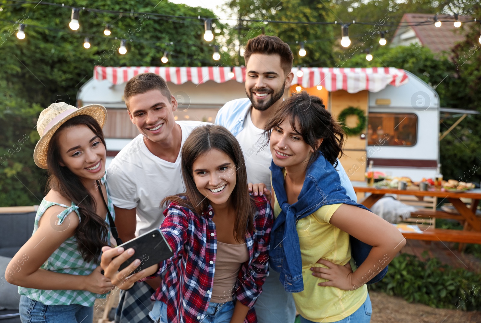 Photo of Happy friends taking selfie near trailer. Camping season