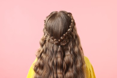 Little girl with braided hair on pink background, back view