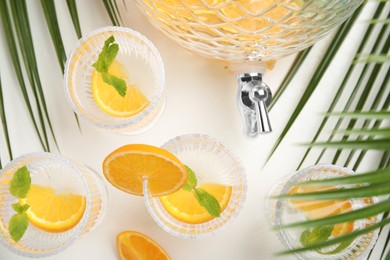 Delicious refreshing drink with orange and mint on white table, flat lay