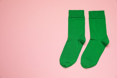 Green socks on pink background, flat lay. Space for text