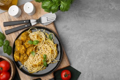 Photo of Delicious pasta and chicken with curry sauce served on grey table, flat lay. Space for text