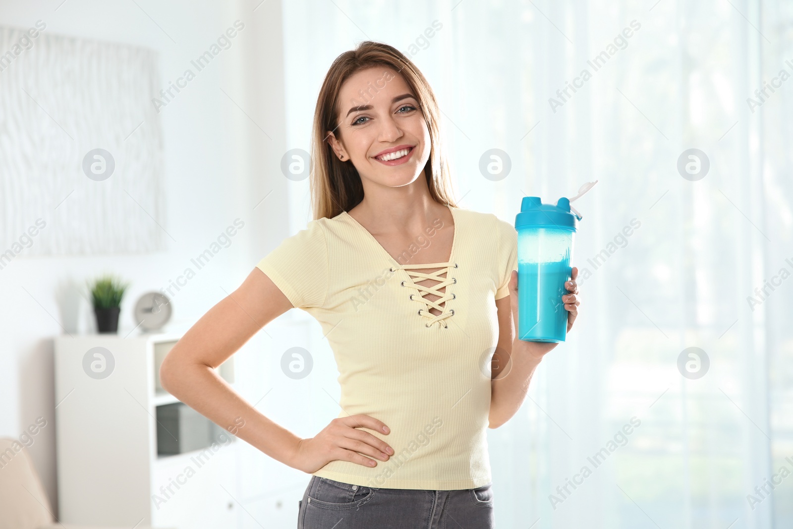 Photo of Young woman with bottle of protein shake at home