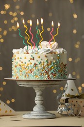 Photo of Beautiful birthday cake with burning candles and decor on white table