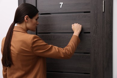 Woman in jacket knocking on door indoors