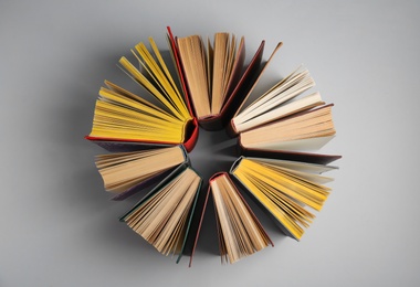 Circle made of hardcover books on grey background, flat lay