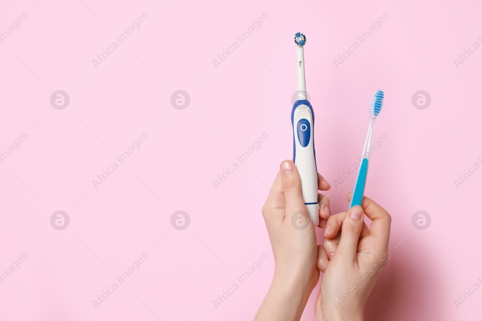 Photo of Woman holding electric and plastic toothbrushes on pink background, closeup. Space for text