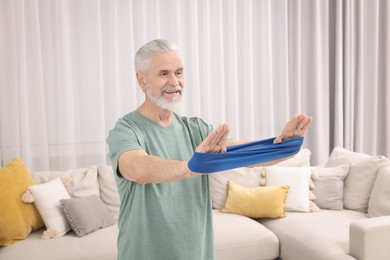 Photo of Senior man doing exercise with fitness elastic band at home