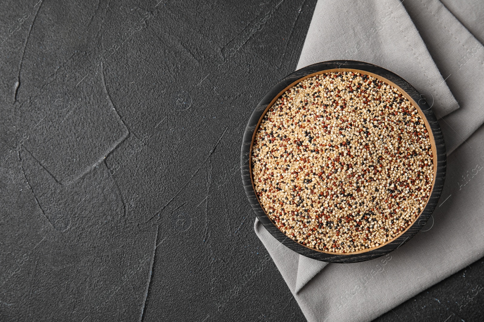 Photo of Plate with mixed quinoa seeds and space for text on dark background, top view