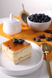 Photo of Piece of delicious cheesecake with blueberries and spoon on white table, closeup. Space for text