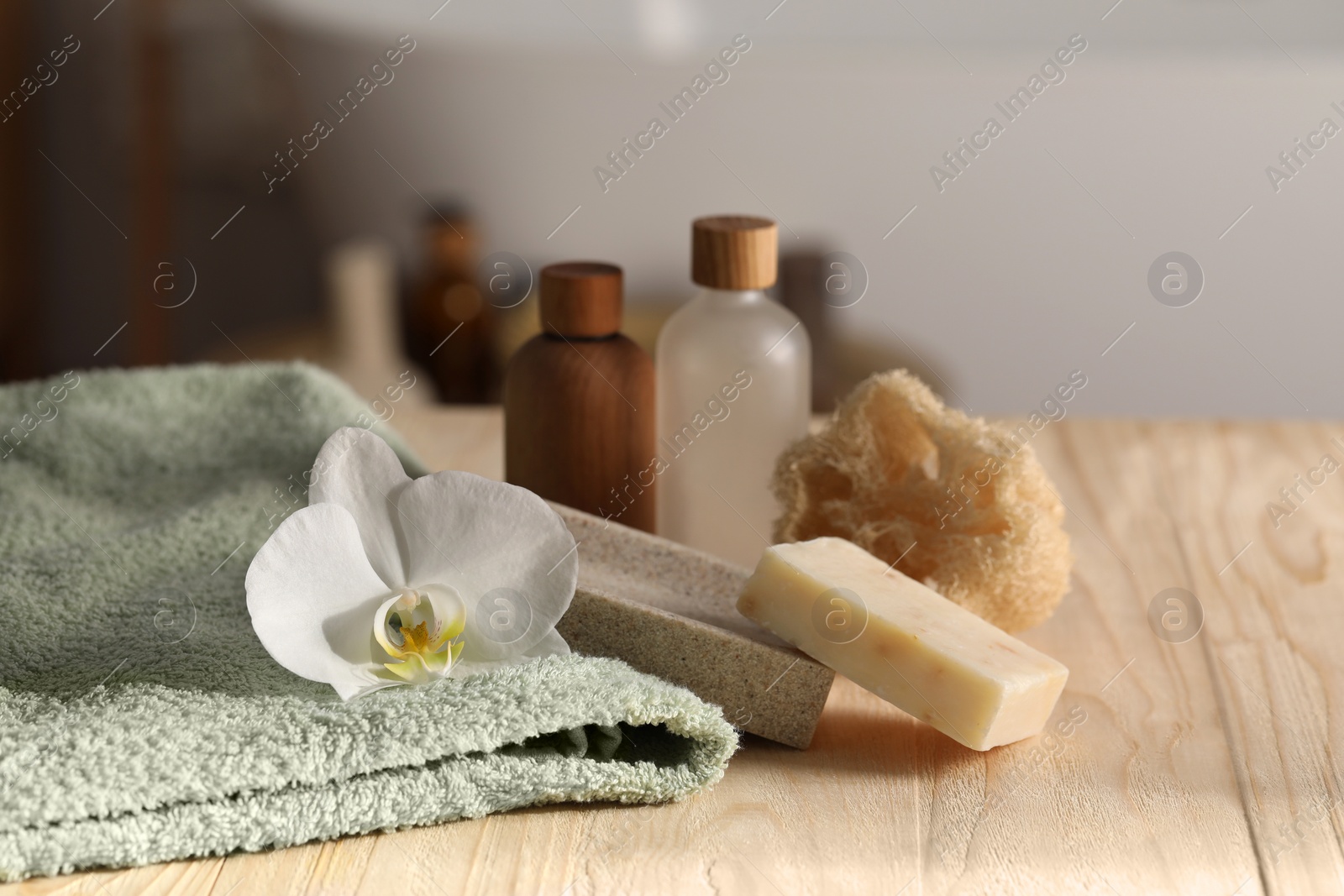 Photo of Composition with spa products and plumeria flower on wooden table in bathroom, closeup. Space for text