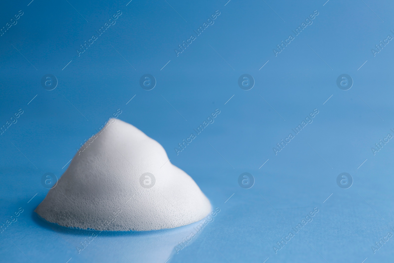 Photo of Fluffy white foam on light blue background, space for text