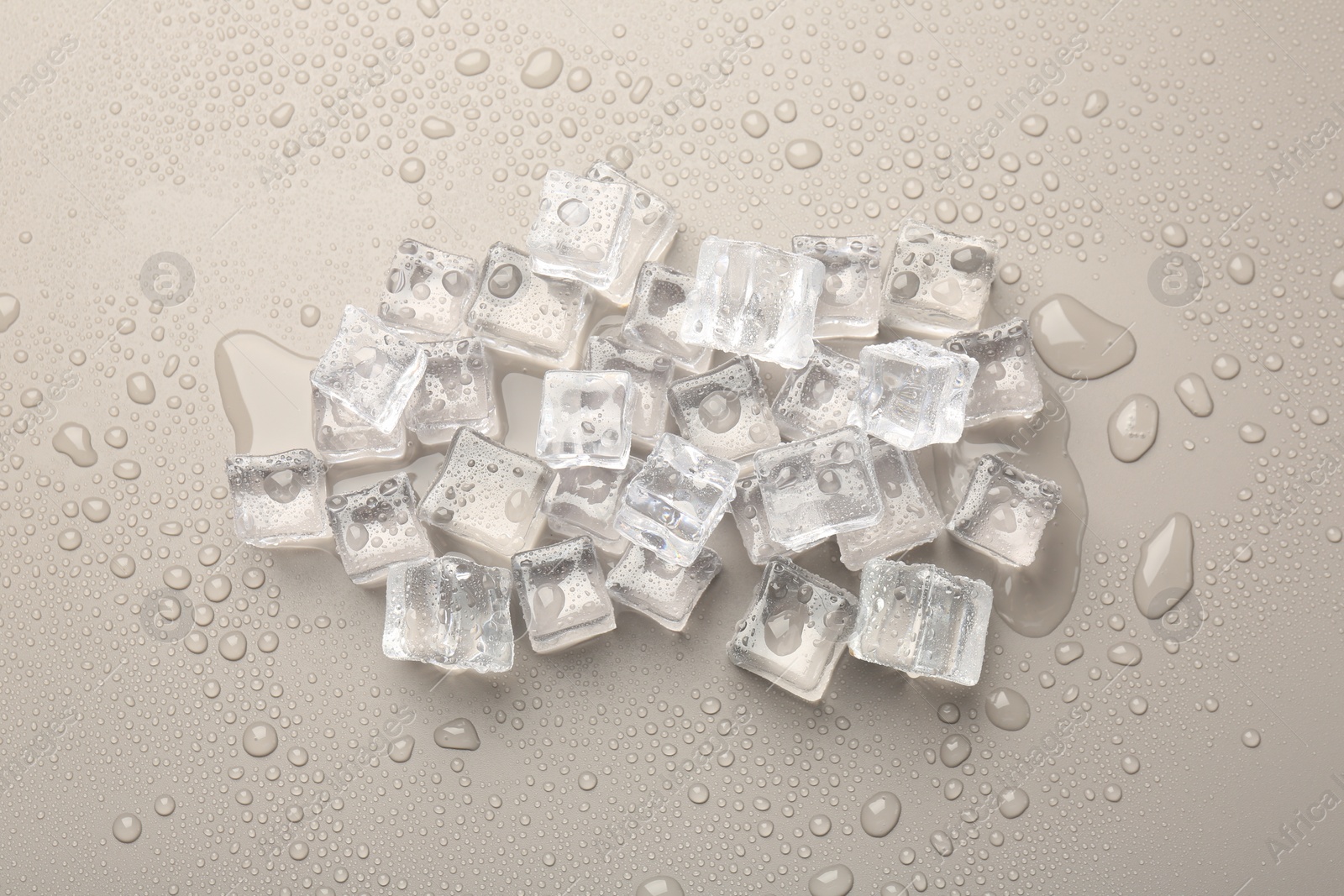 Photo of Pile of melting ice cubes and water drops on light grey background, flat lay