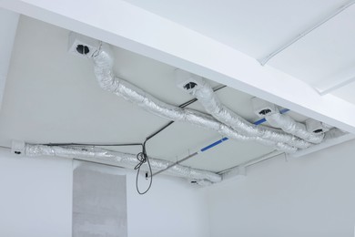 Photo of Empty room with white ceiling and ventilation system during repair
