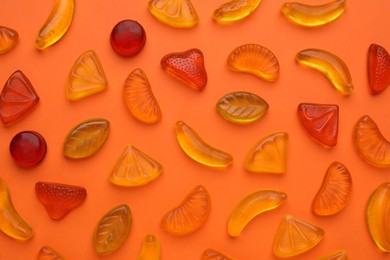 Photo of Delicious gummy fruit candies on orange background, flat lay