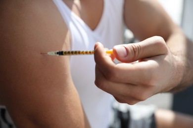Sportsman injecting himself indoors, closeup. Doping concept