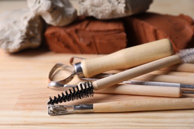 Clay and set of modeling tools on wooden table, closeup