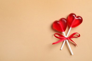 Photo of Sweet heart shaped lollipops on beige background, top view with space for text. Valentine's day celebration