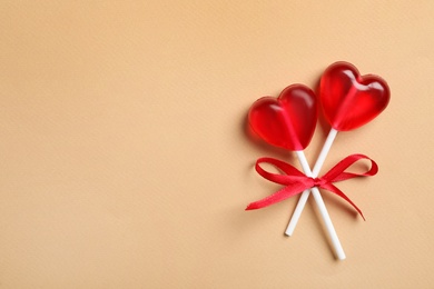 Sweet heart shaped lollipops on beige background, top view with space for text. Valentine's day celebration