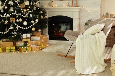 Decorated Christmas tree with gift boxes and fireplace in stylish living room interior