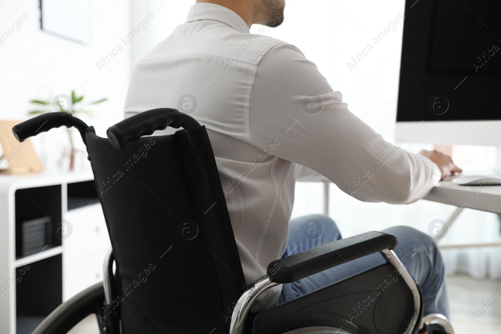 Photo of Young man in wheelchair at workplace, closeup
