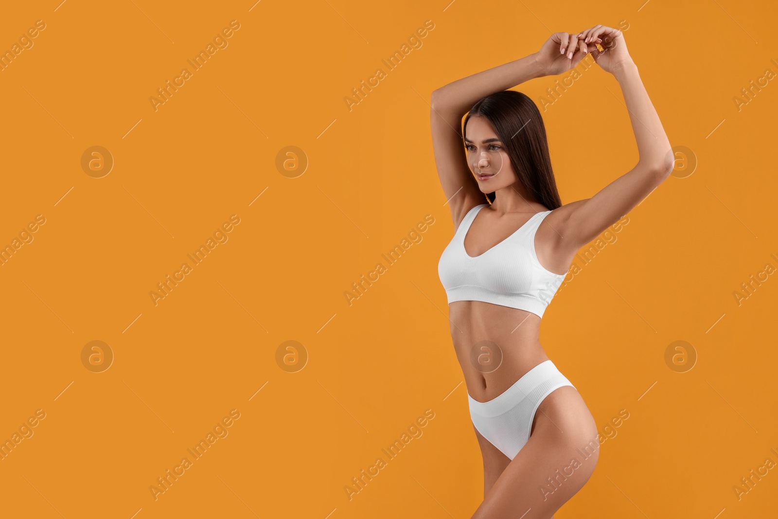 Photo of Young woman in stylish white bikini on orange background. Space for text