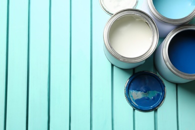 Colorful paint cans on blue wooden background, top view. Space for text