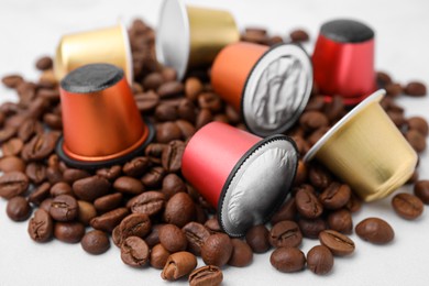 Many coffee capsules and beans on white table, closeup