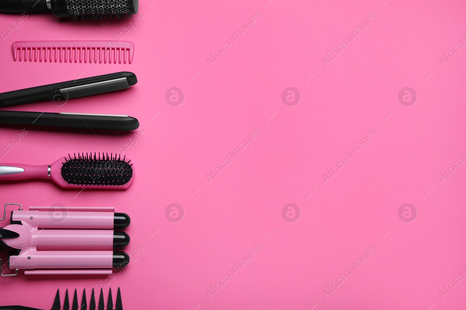 Photo of Flat lay composition of professional hairdresser tools on pink background, space for text