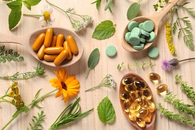 Different pills, herbs and flowers on wooden table, flat lay. Dietary supplements