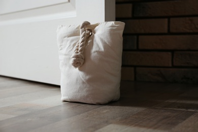 Photo of Stuffed bag holding wooden door at home