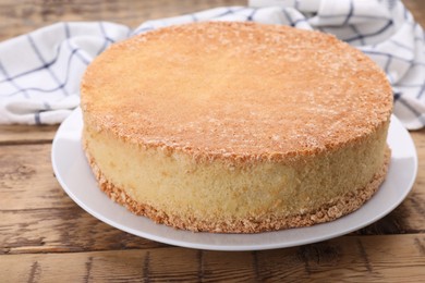 Plate with delicious sponge cake on wooden table, closeup