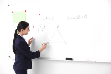 Photo of Young teacher near whiteboard in modern classroom