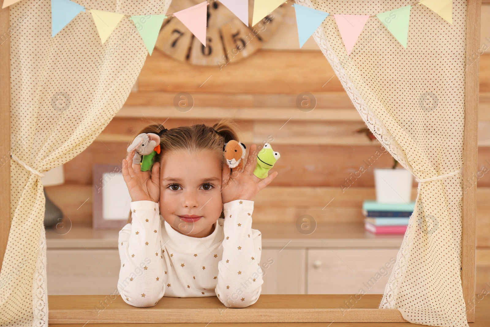 Photo of Cute little girl performing puppet show at home