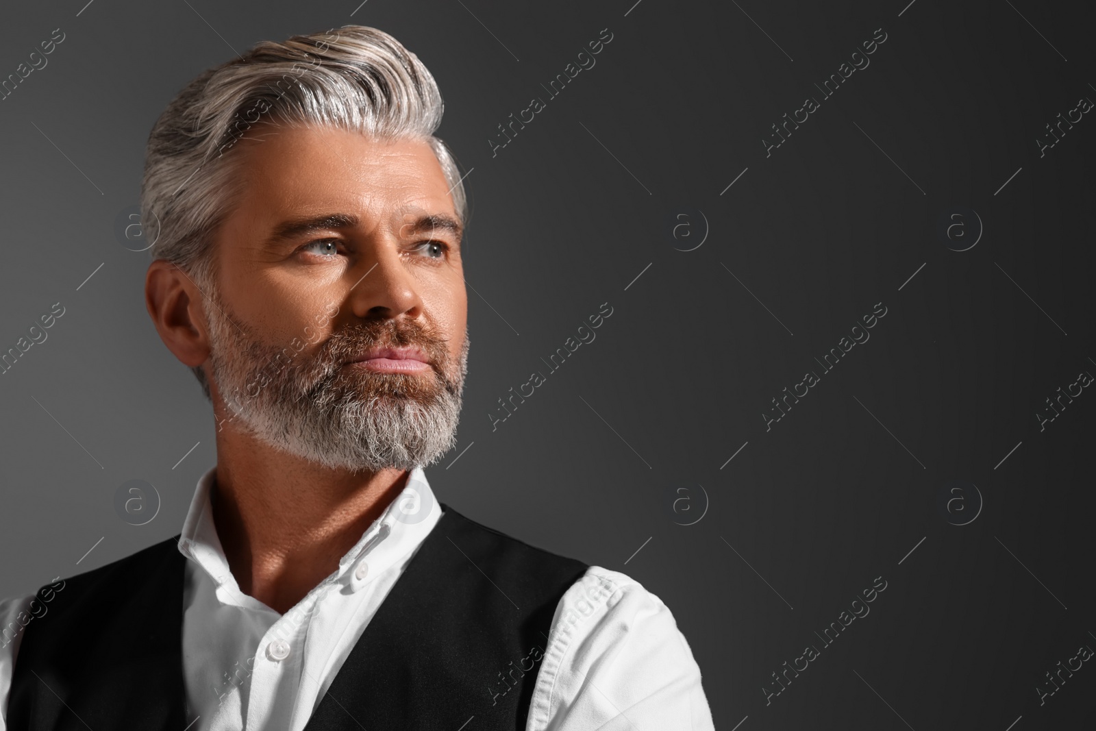 Photo of Portrait of confident man with beautiful hairstyle on dark background. Space for text