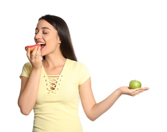 Photo of Concept of choice. Woman eating doughnut and holding apple on white background