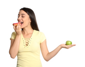 Concept of choice. Woman eating doughnut and holding apple on white background