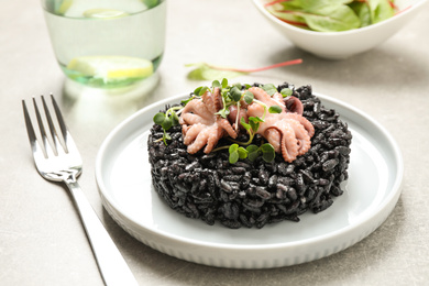 Photo of Delicious black risotto with seafood served on plate