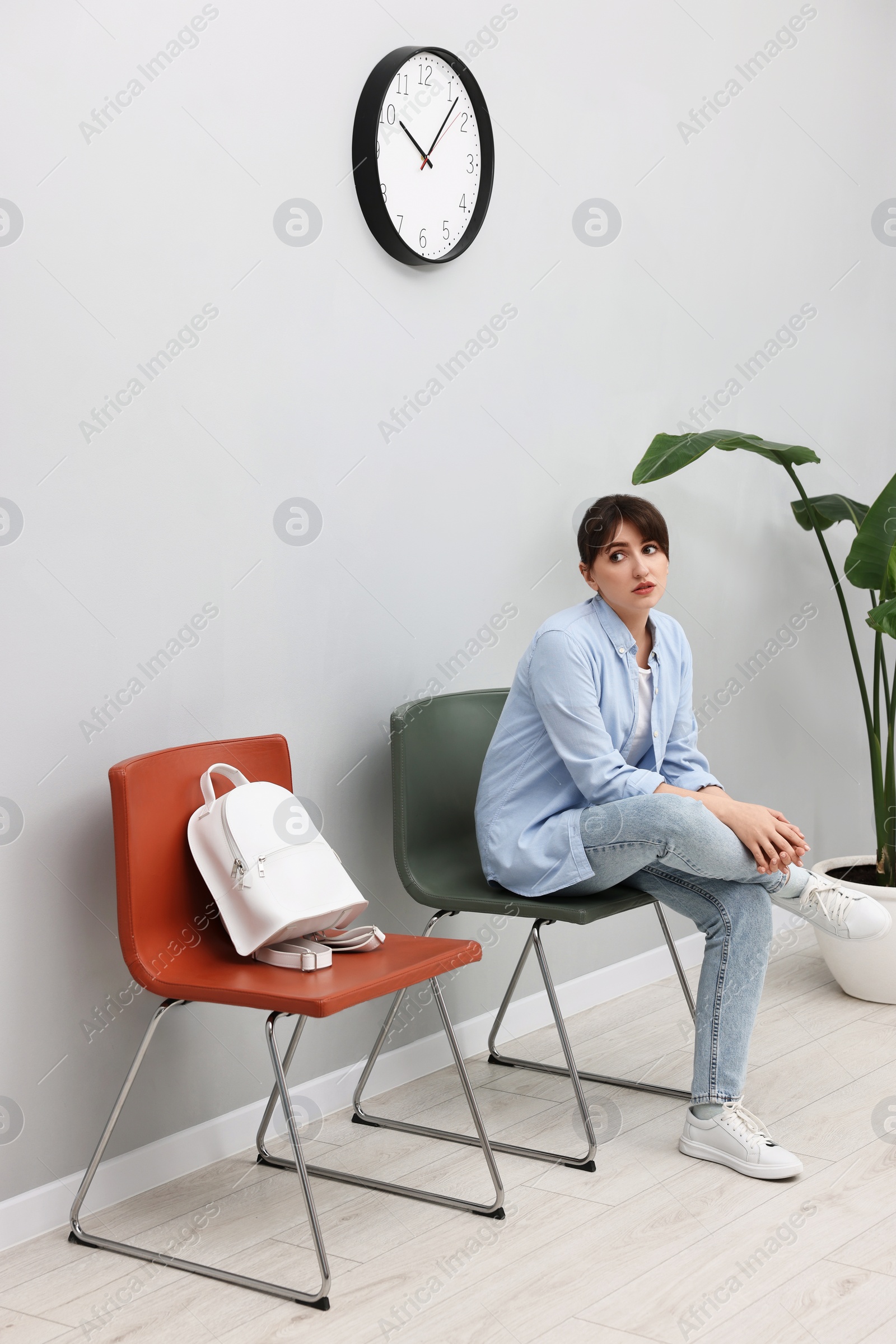 Photo of Woman sitting on chair and waiting for appointment indoors