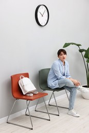 Woman sitting on chair and waiting for appointment indoors